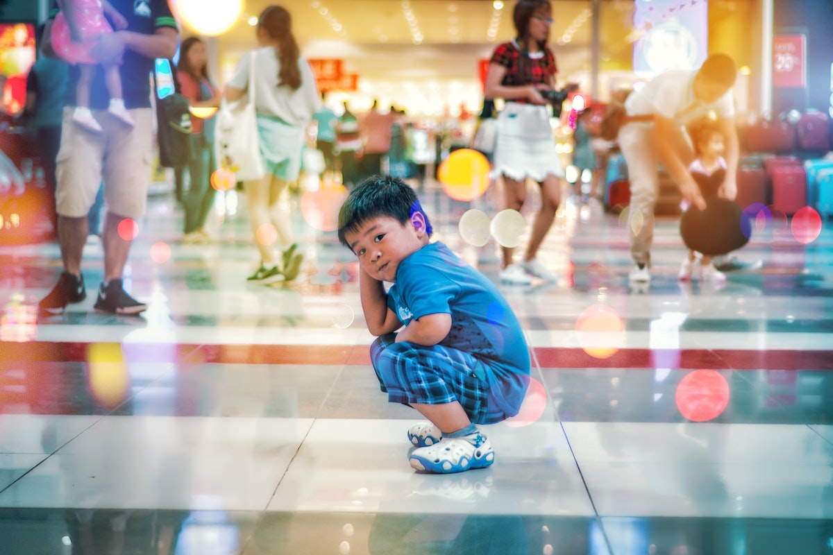 Boy Squatting on White Floor Tile